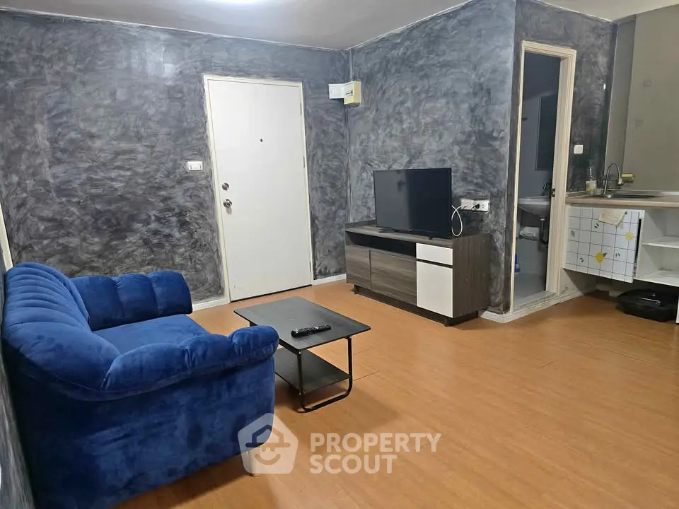 Modern living room with stylish blue sofa and sleek TV unit, featuring contemporary decor and wooden flooring.