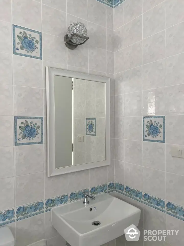 Pristine bathroom with elegant floral tile accents and a large mirror, creating a serene and refreshing space for relaxation.