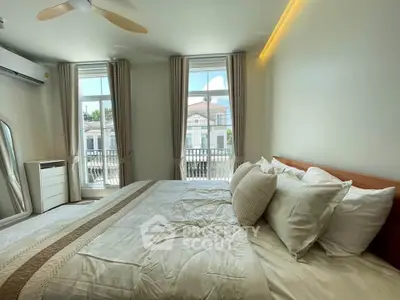 Spacious bedroom with large windows and elegant decor in modern home.