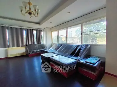 Spacious living room with large windows and modern furniture, ideal for urban living.