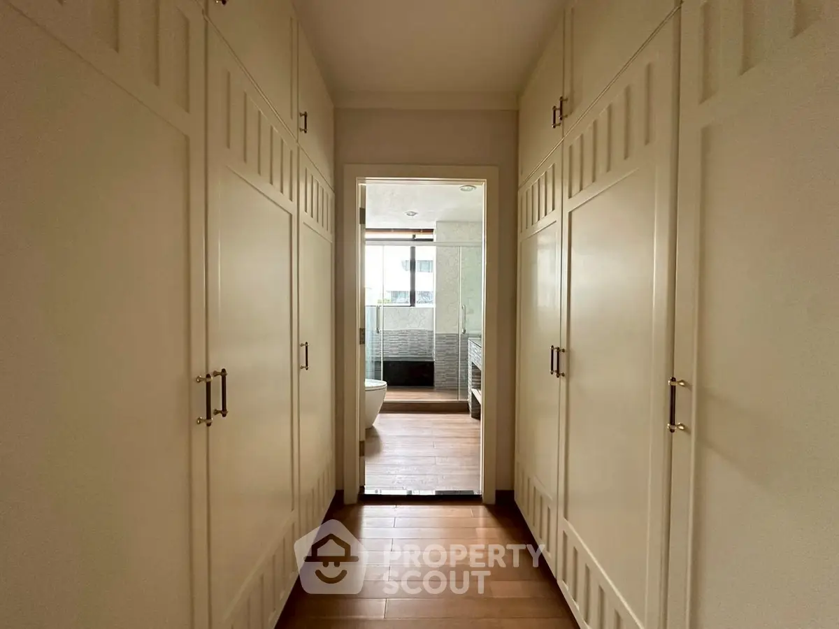 Spacious walk-in closet leading to a modern bathroom with natural light.
