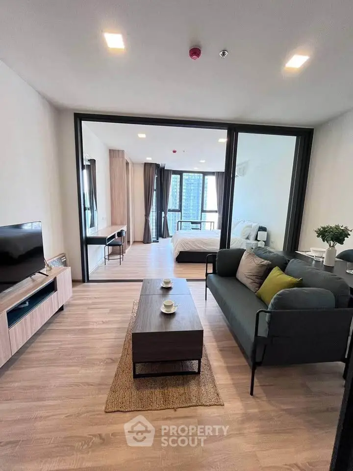Modern open-plan living room with stylish furniture and large windows offering city views.