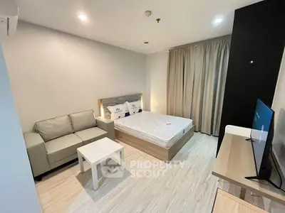 Modern studio apartment with cozy bed and stylish sofa in open layout.