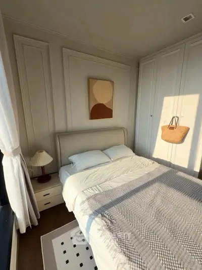 Cozy bedroom with elegant decor and natural light, featuring a stylish bed and modern artwork.