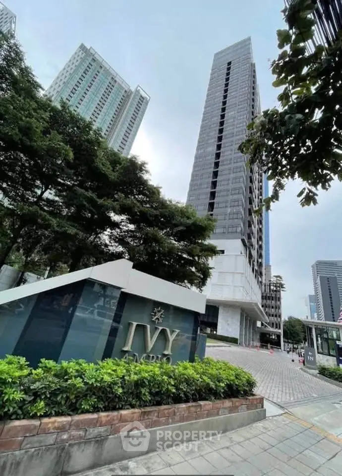 Modern high-rise building with lush greenery and sleek entrance in urban setting.