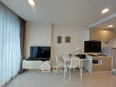 Modern living room with sleek kitchen and dining area, featuring contemporary furniture and natural light.