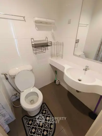 Compact modern bathroom with wall-mounted sink and toilet, featuring sleek white tiles and practical storage solutions.