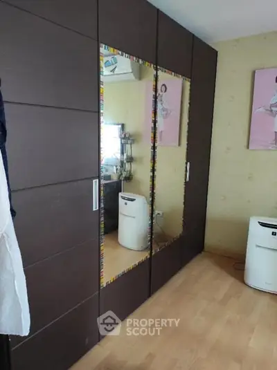 Spacious bedroom with large mirrored wardrobe and wooden flooring