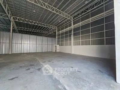 Spacious industrial warehouse with high ceilings and metal framework, ideal for storage or manufacturing.