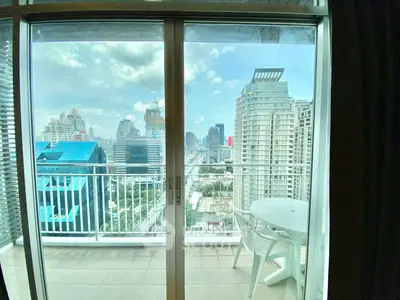 Stunning city view from modern balcony with glass doors and outdoor seating.