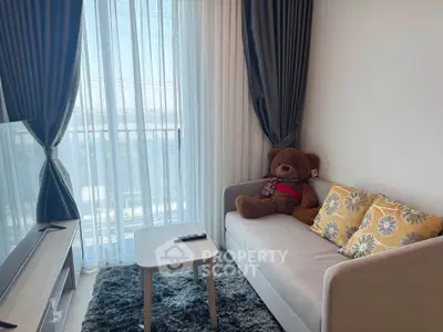 Cozy living room with plush sofa, teddy bear, and large window with curtains.