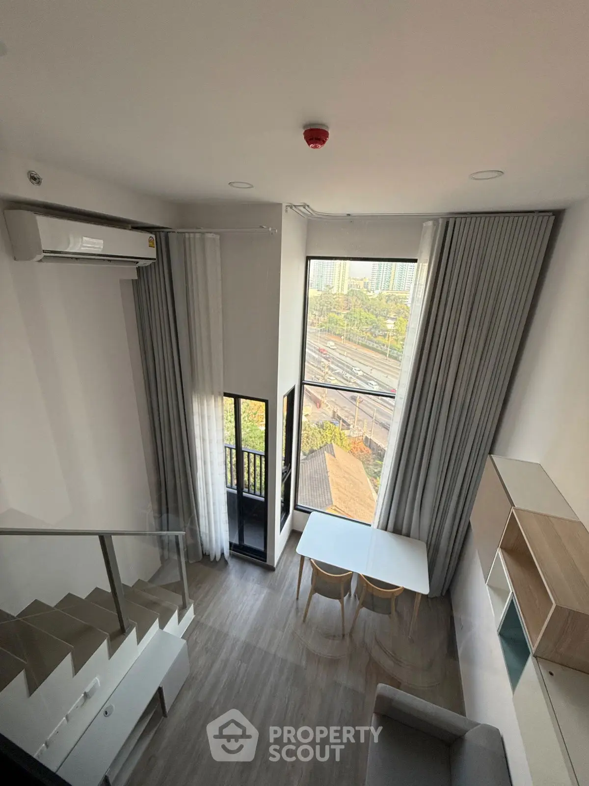 Modern loft-style living room with large windows and city view, featuring sleek furniture and stylish decor.