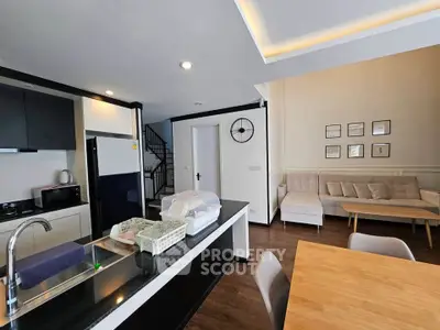 Modern open-plan kitchen and living room with stylish decor and natural light.