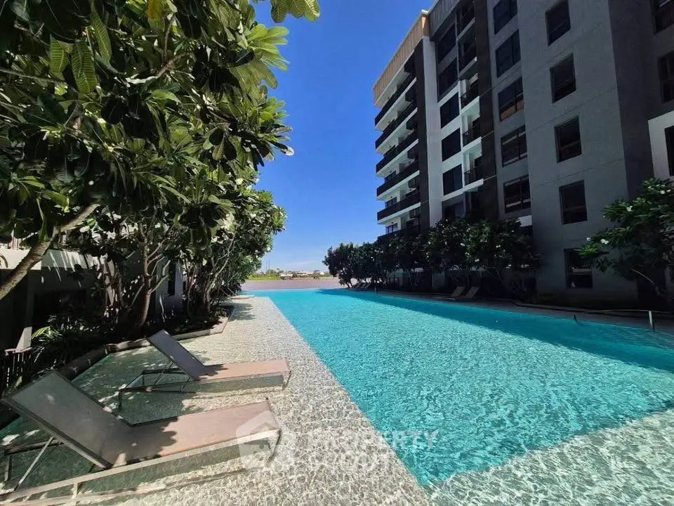 Luxurious apartment building with stunning outdoor pool and lush greenery, perfect for relaxation and leisure.