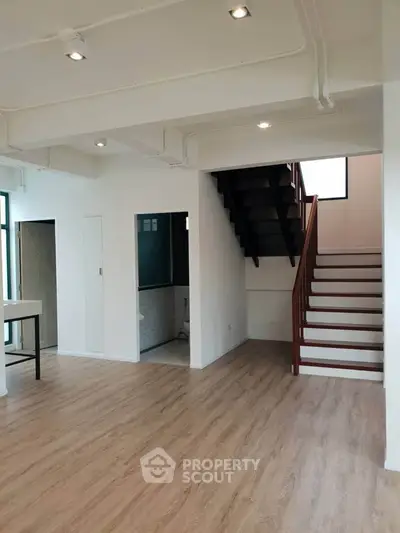 Spacious modern interior with wooden flooring and staircase, ideal for stylish living.