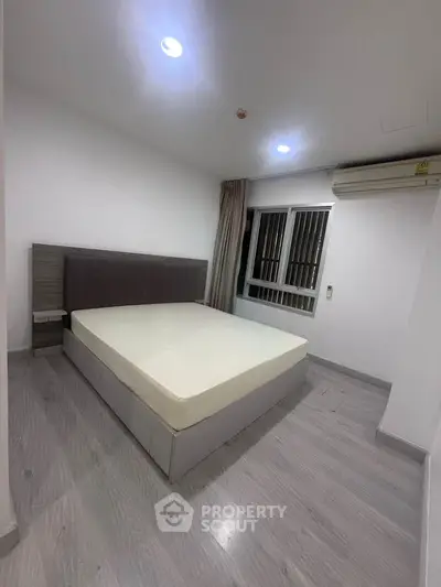 Modern minimalist bedroom with sleek flooring and large window for natural light.