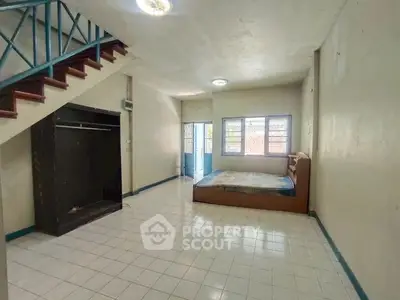 Spacious bedroom with tiled floor and open closet under staircase