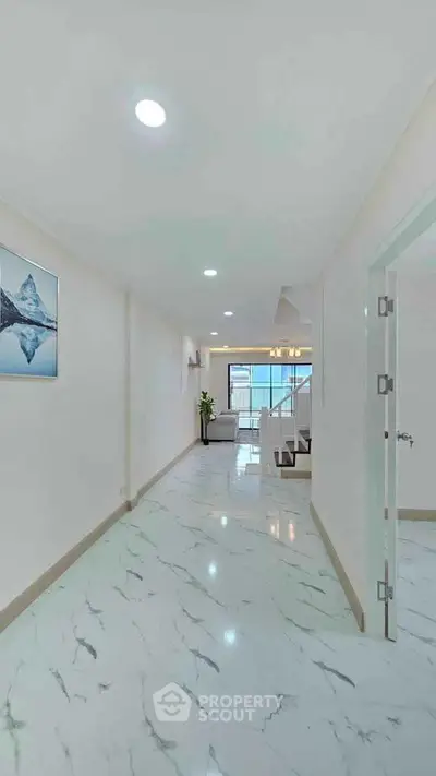 Spacious hallway leading to a modern living room with marble flooring and elegant decor.