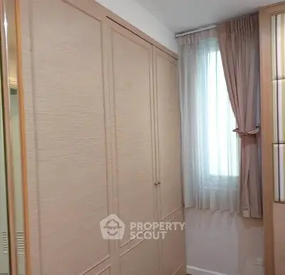 Elegant bedroom with built-in wardrobe and natural light through window.