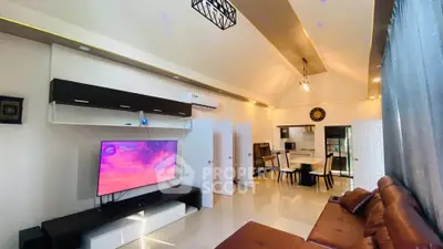Spacious living room with modern decor and open layout, featuring a large TV and comfortable seating.