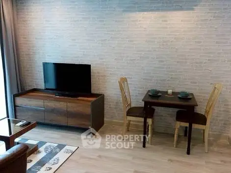 Modern living room with TV and dining area, featuring stylish brick wall and wooden furniture.
