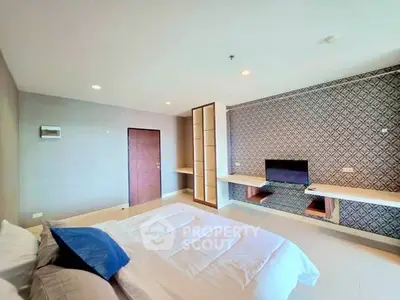 Spacious modern bedroom with stylish decor and built-in TV unit, perfect for relaxation.
