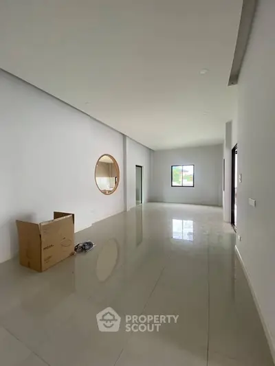 Spacious modern living room with glossy tile flooring and large windows for natural light.