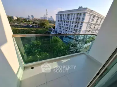 Spacious balcony with glass railing offering stunning city views in modern apartment building.