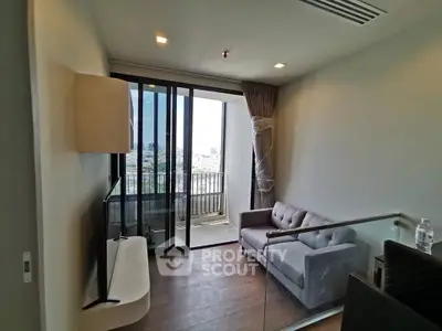 Modern living room with balcony view in a high-rise apartment, featuring sleek furniture and natural light.