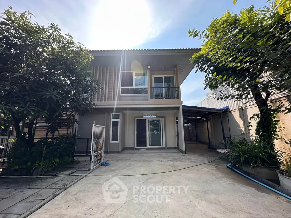 Charming two-story house with spacious driveway and lush greenery, perfect for family living.