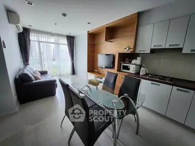 Modern open-layout living room with kitchen, featuring sleek furniture and large windows for natural light.