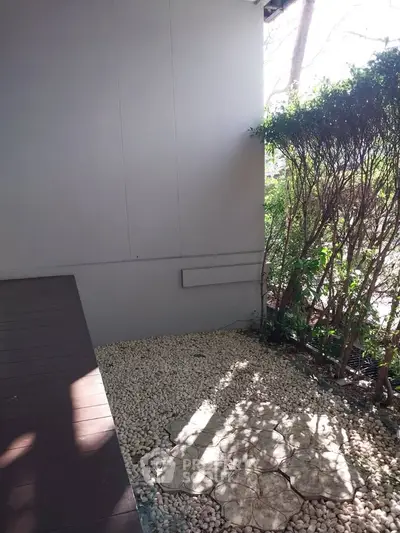 Charming outdoor garden area with pebble pathway and lush greenery, perfect for relaxation and outdoor enjoyment.