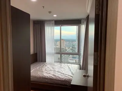 Modern bedroom with large window offering stunning city view in high-rise apartment.