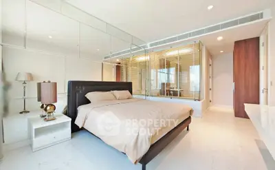 Luxurious bedroom with modern design and mirrored walls, featuring a cozy bed and elegant decor.