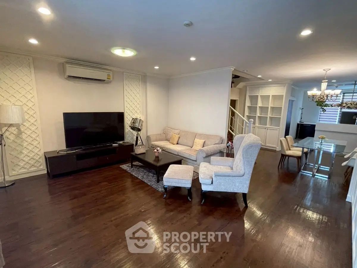 Spacious living room with elegant decor and dining area, featuring hardwood floors and modern lighting.