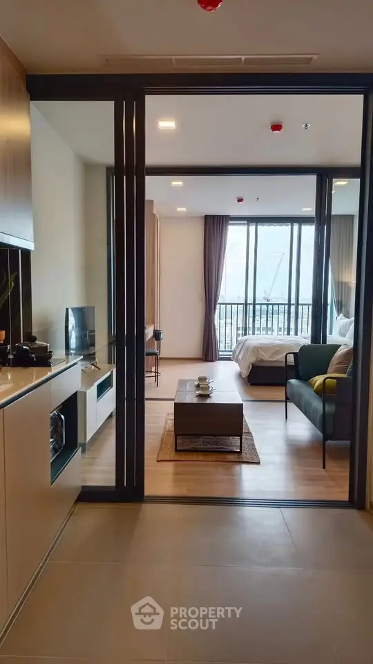Modern open-layout apartment with stylish kitchen and cozy living area leading to a bright bedroom.