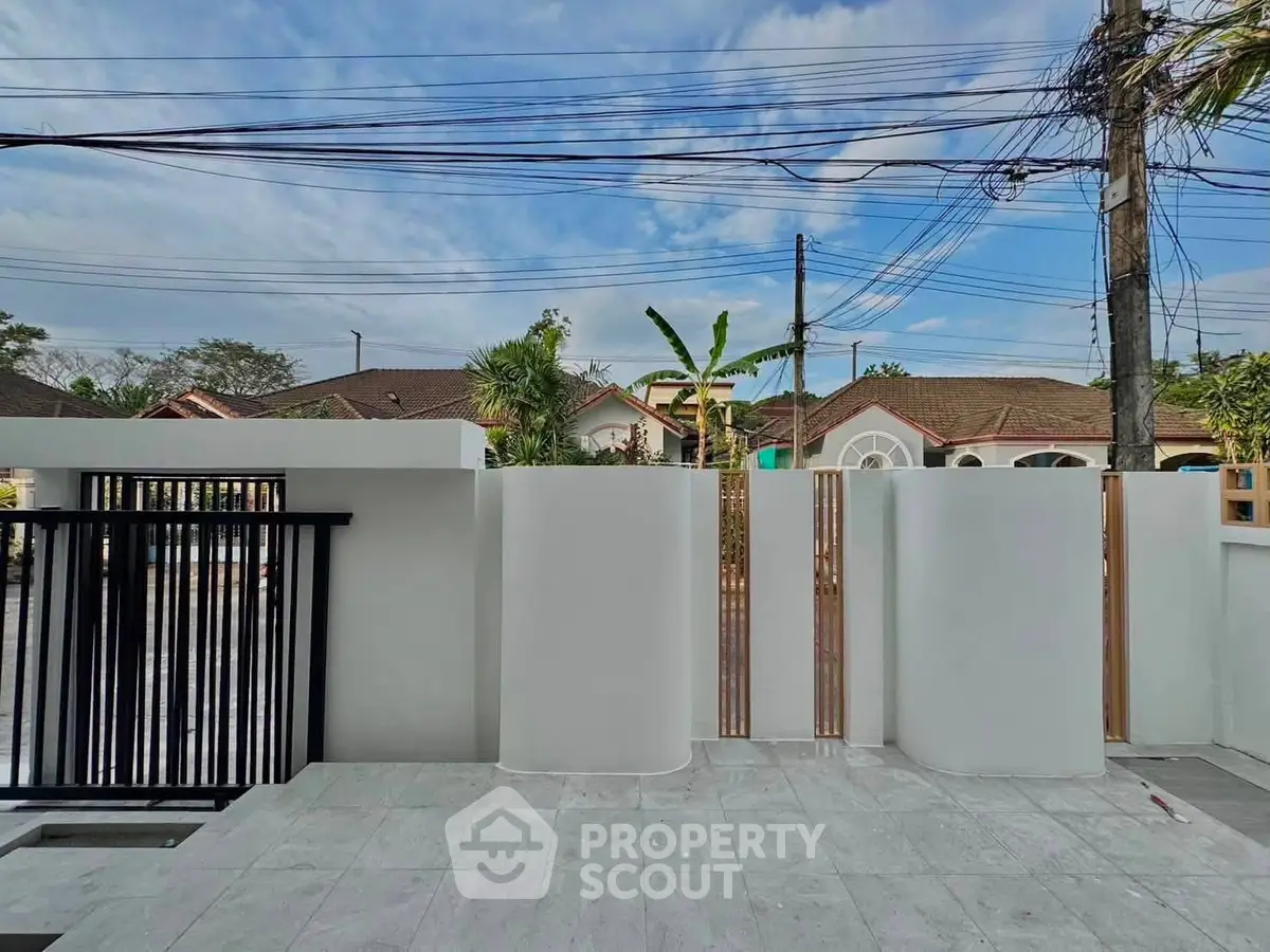 Modern exterior view of a stylish residential property with sleek white walls and a spacious tiled patio.