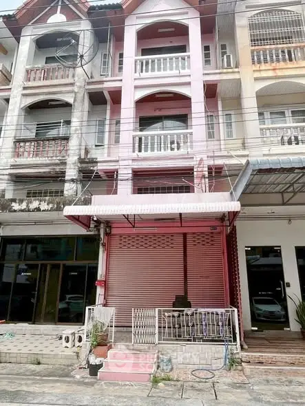 Charming multi-story pink townhouse with balcony in vibrant urban setting.