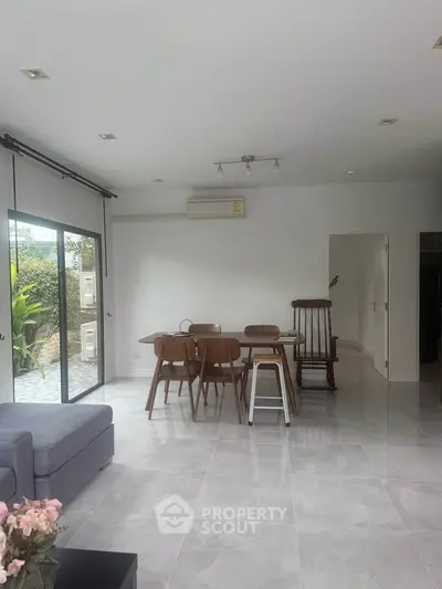 Spacious modern living room with dining area and garden view, featuring sleek furniture and natural light.