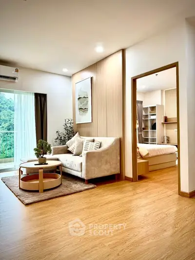 Modern living room with cozy sofa and bedroom view, featuring elegant decor and natural light.