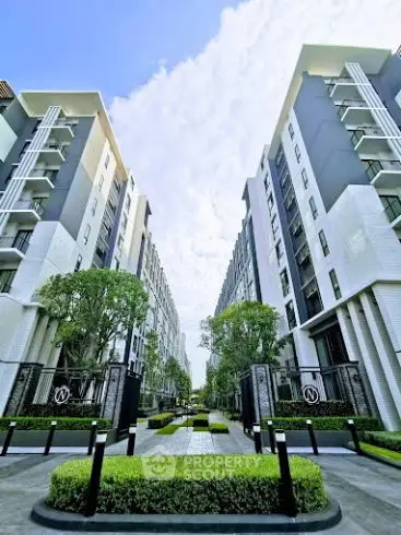 Modern apartment complex with lush landscaping and clear blue sky