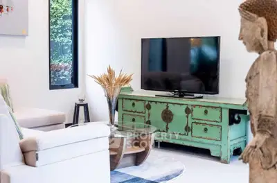 Chic living room with vintage green console, modern TV, and elegant decor.