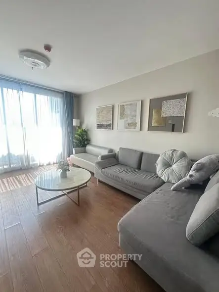 Spacious living room with modern gray sofas and large windows for natural light.