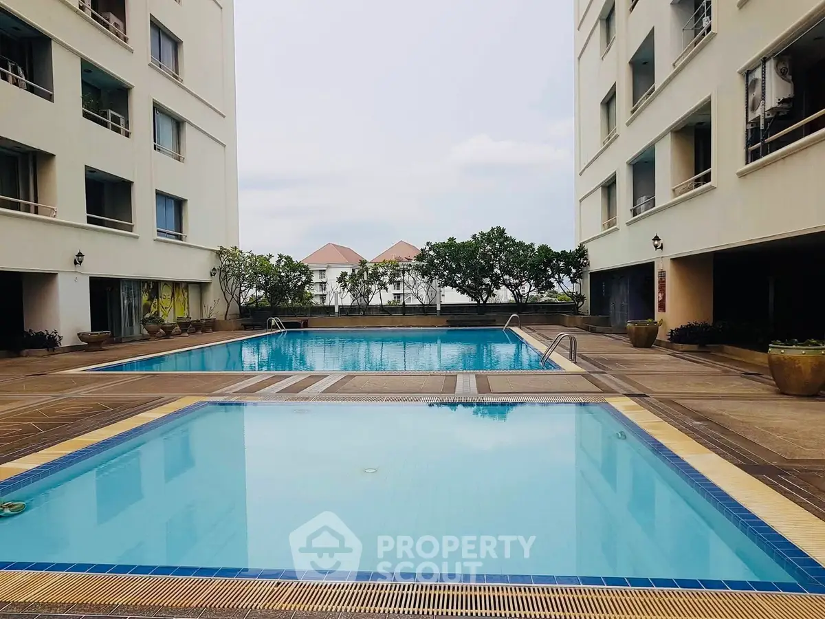 Luxurious apartment complex with two pristine swimming pools and modern architecture.