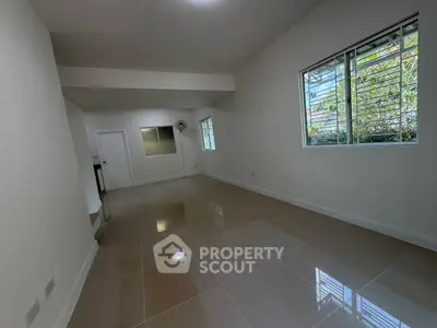 Spacious modern living room with glossy tiled floors and large windows for natural light.