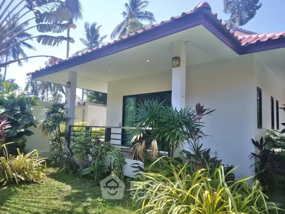 Charming tropical bungalow with lush garden and inviting porch.