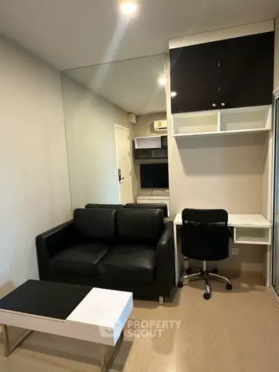 Modern living room with sleek black sofa, stylish desk, and contemporary decor.