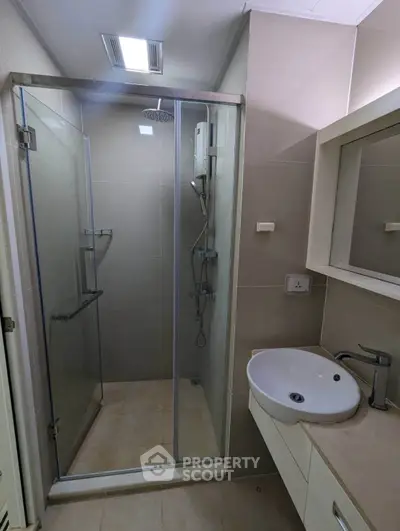 Modern bathroom with glass shower enclosure and sleek vanity in contemporary apartment.