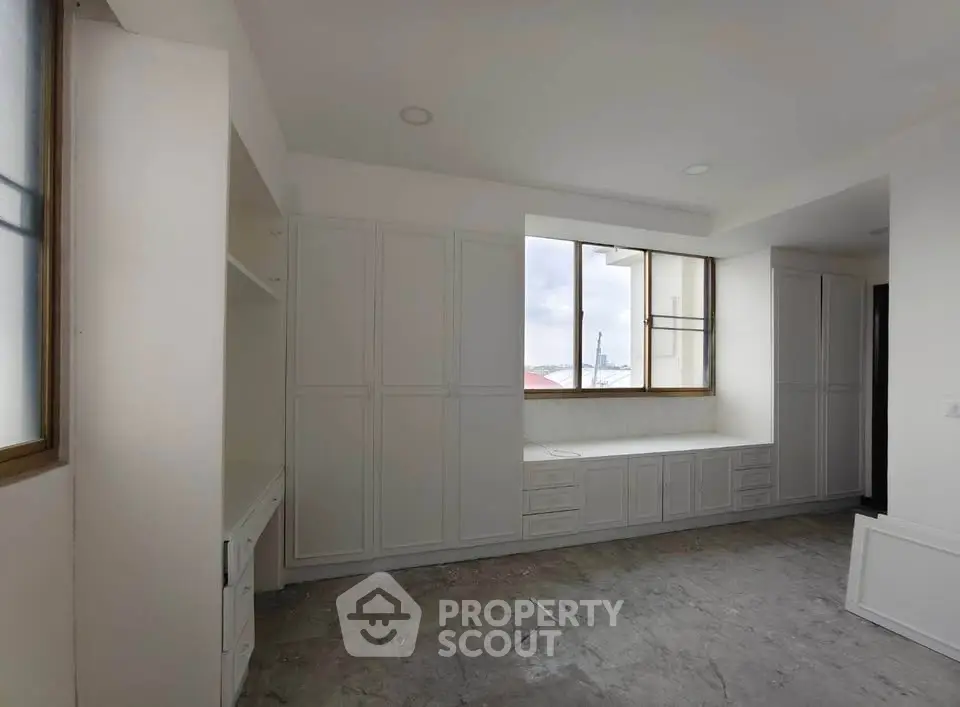 Spacious room with built-in storage and large window offering natural light.