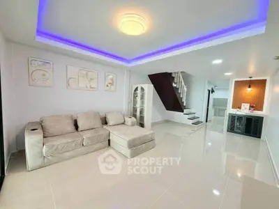 Spacious modern living room with stylish lighting and elegant staircase in a contemporary home.